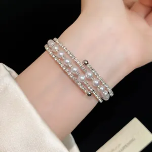 Detailed view of multilayered silver bracelet with pearls and rhinestones on wrist