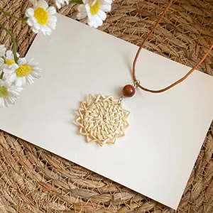 Detailansicht einer handgefertigten Halskette mit geflochtenem Rattan-Anhänger und Perle.