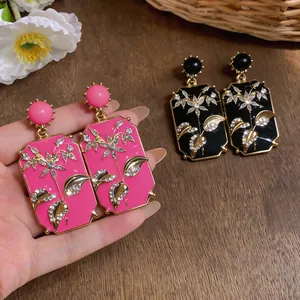 Primo piano di orecchini vintage quadrati con strass floreali e finitura in smalto rosa