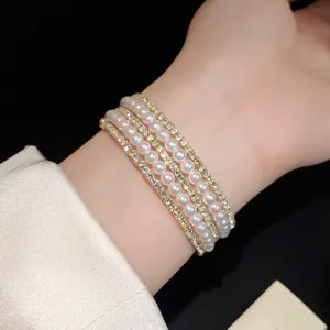 Detail view of an elegant multi-layer pearl and rhinestone cuff bracelet on a wrist
