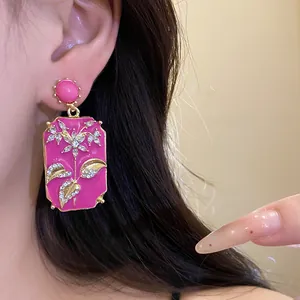 Detail of vintage pink enamel square earrings featuring elegant rhinestone floral motifs