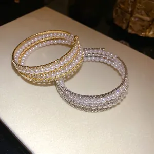 Macro detail of multi-layer pearl and rhinestone open bracelets in gold and silver