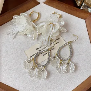 Detail showing elegant flower tassel earrings and rhinestone teardrop hoops on fabric