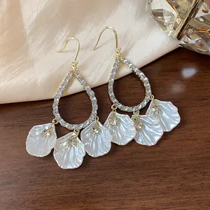Detailed view of elegant drop earrings with white shell petals and shimmering rhinestones