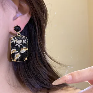 Close-up of vintage black enamel rectangular earrings featuring crystal floral design