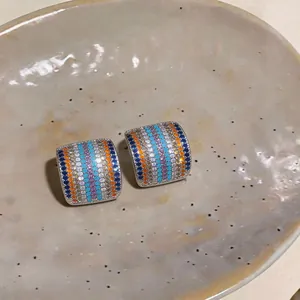 Primer plano de pendientes de botón cuadrados con hileras de circonitas de colores