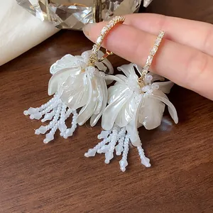 Detailed macro view of elegant white flower tassel earrings with crystals