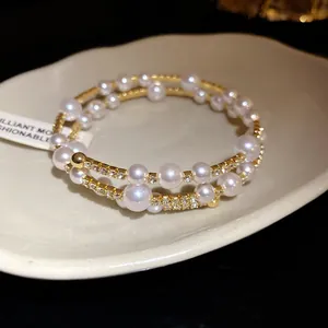 Vue détaillée d'un élégant bracelet triple couche doré avec perles et strass brillants