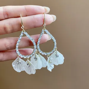 Close-up of elegant water-drop earrings with white floral petals and shiny crystals