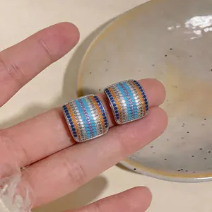 Primer plano de pendientes de botón cuadrados con circonitas de colores