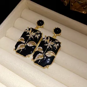 Close-up of vintage rectangular enamel earrings with floral rhinestone patterns