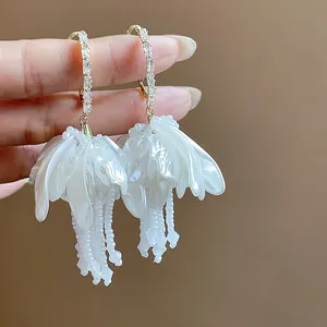 Detailed shot of white flower tassel earrings with sparkling rhinestones and pearls.