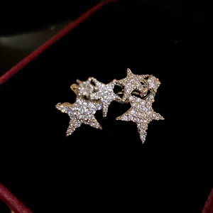 Macro detail of zircon-encrusted star ear clips in a black velvet jewelry box