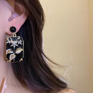 Close-up of vintage palace-style black enamel earrings with floral diamond inlay.
