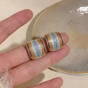 Vista detallada de pendientes cuadrados de oro con filas de circonitas