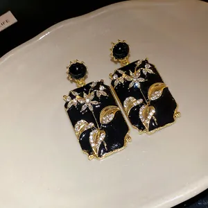 Detailed close-up of vintage black enamel square earrings with sparkling floral crystals.