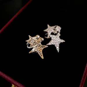 Close-up of zircon-encrusted silver star ear cuffs on black velvet background