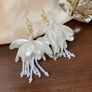 Detail view of pearlescent flower petal earrings with beaded tassels and rhinestones