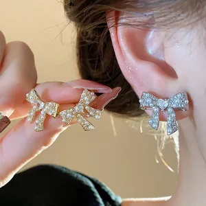 Close-up detail of exquisite gold and silver pearl and crystal bow-knot stud earrings.