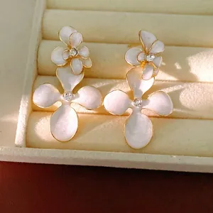 Elegant white enamel flower stud earrings with shimmering rhinestones and gold trim