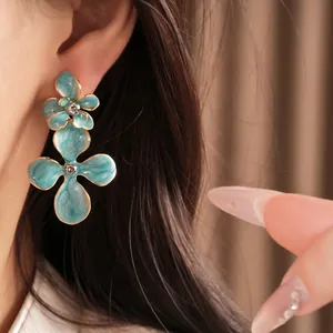 Elegant teal enamel flower earrings with sparkling rhinestone centers and silver needles