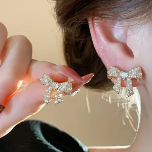 Close-up of elegant 18k gold plated bow earrings with delicate pearls and crystals