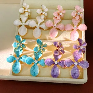 Close-up of colorful enamel flower earrings with rhinestone centers in a beige jewelry box