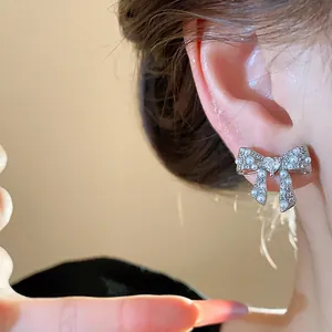Close-up shot of elegant silver bow earrings featuring small pearls and crystals on ear