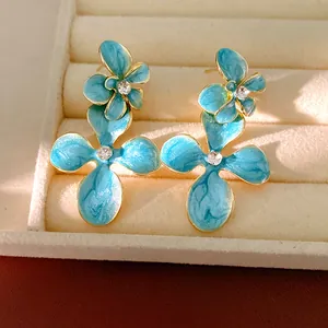 Exquisite close-up of blue enamel flower earrings featuring sparkling rhinestone centers