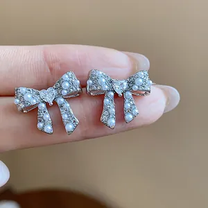 Macro shot of bow earrings with shimmering pearls and heart-shaped center crystals