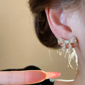 Detailed macro view of a gold-plated bow earring with pearls and heart-shaped center stone