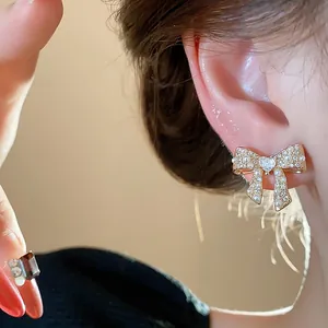 Close-up of elegant bowknot pearl stud earrings with 18k gold plating on an ear