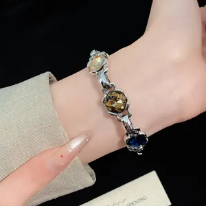 Close-up of a vintage silver bracelet with multicolored rhombic stones worn on a wrist.