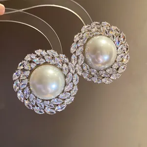 Close-up of elegant vintage pearl stud earrings surrounded by sparkling marquise zircons