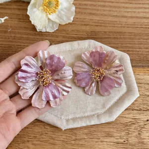 Dettaglio di orecchini a fiore dipinti rosa e viola con una texture metallica opaca