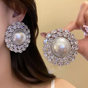 Detailed close-up of elegant large pearl stud earrings with marquise zircon stone cluster