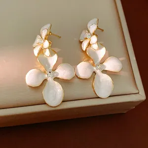 Elegant white enamel flower earrings with gold finish and rhinestone details