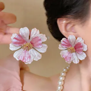 Vista ravvicinata dettagliata di grandi orecchini a fiore rosa e bianco indossati all'orecchio