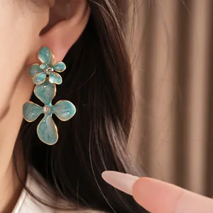 Detailed view of turquoise flower earrings with rhinestone center and enamel finish