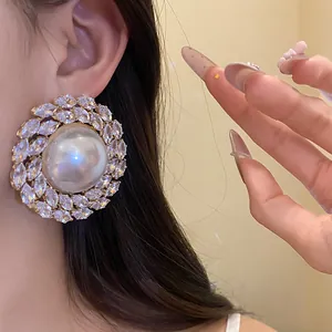 Detail view of a vintage-style large pearl earring surrounded by sparkling zircons