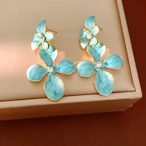 Close-up of elegant blue enamel flower earrings with sparkling rhinestone centers.