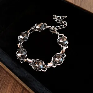 Macro detail of silver-toned bracelet with dark grey faceted crystals on black velvet