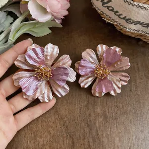 Dettaglio ravvicinato di grandi orecchini a lobo a forma di fiore rosa e viola