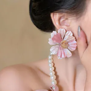 Primo piano di grandi orecchini a fiore rosa e bianchi indossati da una modella