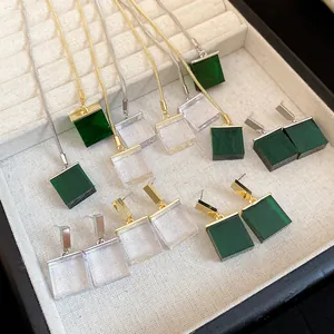 Detail shot of emerald green and clear square resin pendant jewelry set on display.
