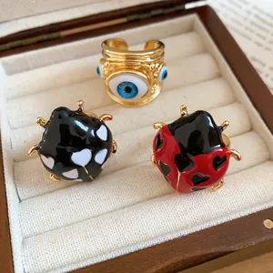 Close-up view of vibrant enamel ladybug and evil eye adjustable rings in jewelry box