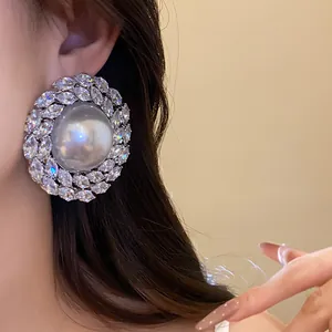 Detail of vintage luxury pearl stud earrings with sparkling cubic zirconia stones on a model
