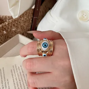 Close-up detail of a gold-plated open ring with a unique blue evil eye design motif