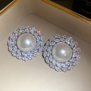 Detailed close-up of vintage style stud earrings with large central pearl and zircon halo