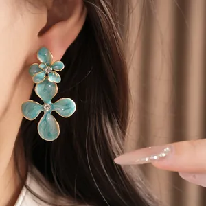 Macro view of blue enamel flower earrings with sparkling central crystals and gold edges